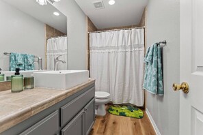A bathroom with a white sink, mirror, and toilet. There are towels and a shower curtain. - Phoenix Desert Paradise | Pool & Jacuzzi | Grill!, Phoenix Desert Paradise | Pool & Jacuzzi | Grill! (Joshua Tree)