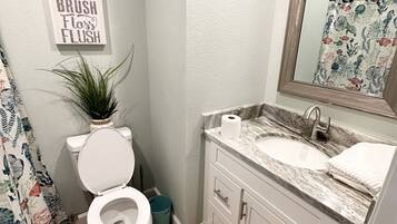 A bathroom with a toilet, sink, and mirror. There is a sign on the wall that says "Wash Brush Floss Flush."