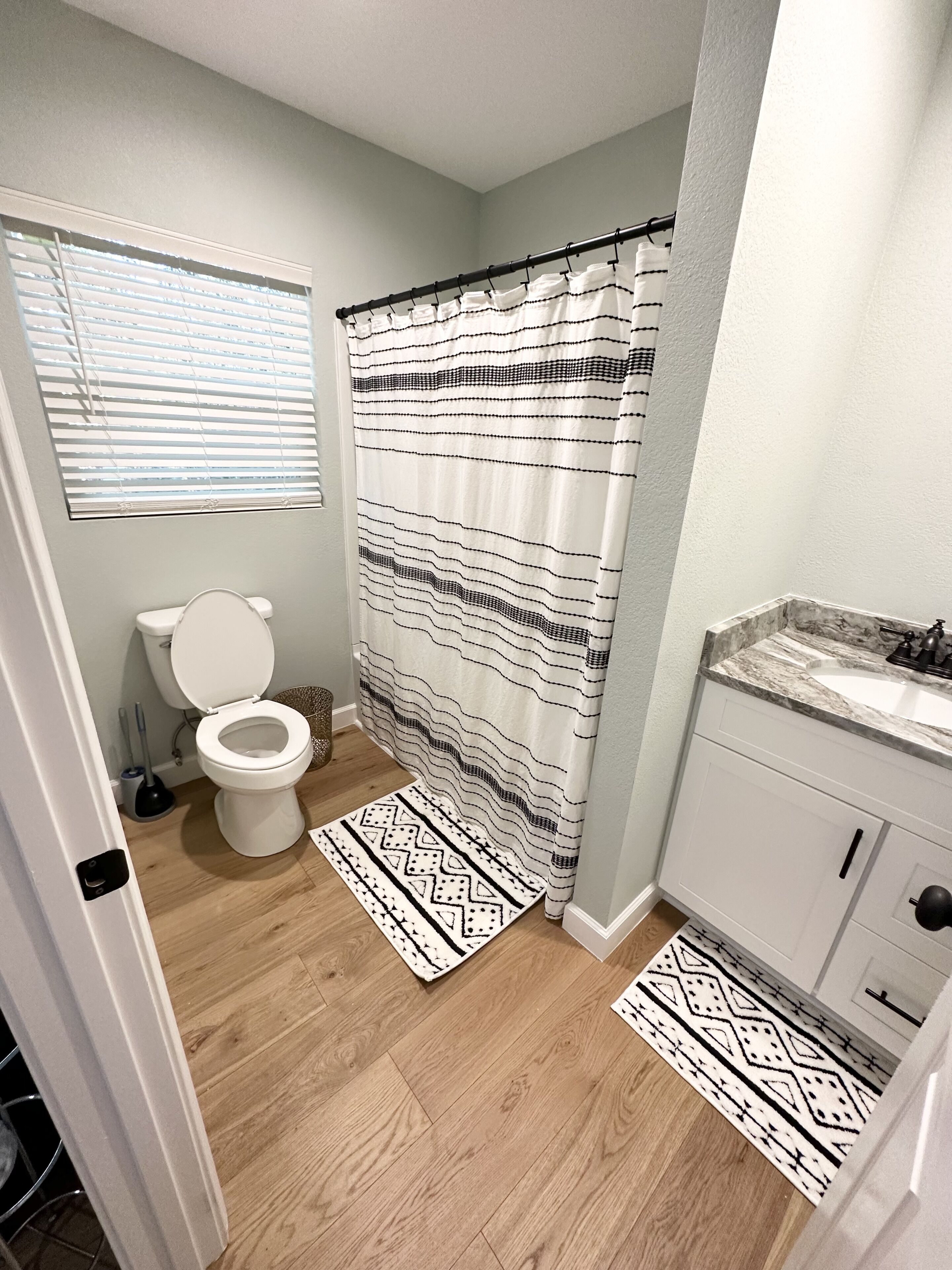 A bathroom with a toilet, a shower curtain, and a sink.