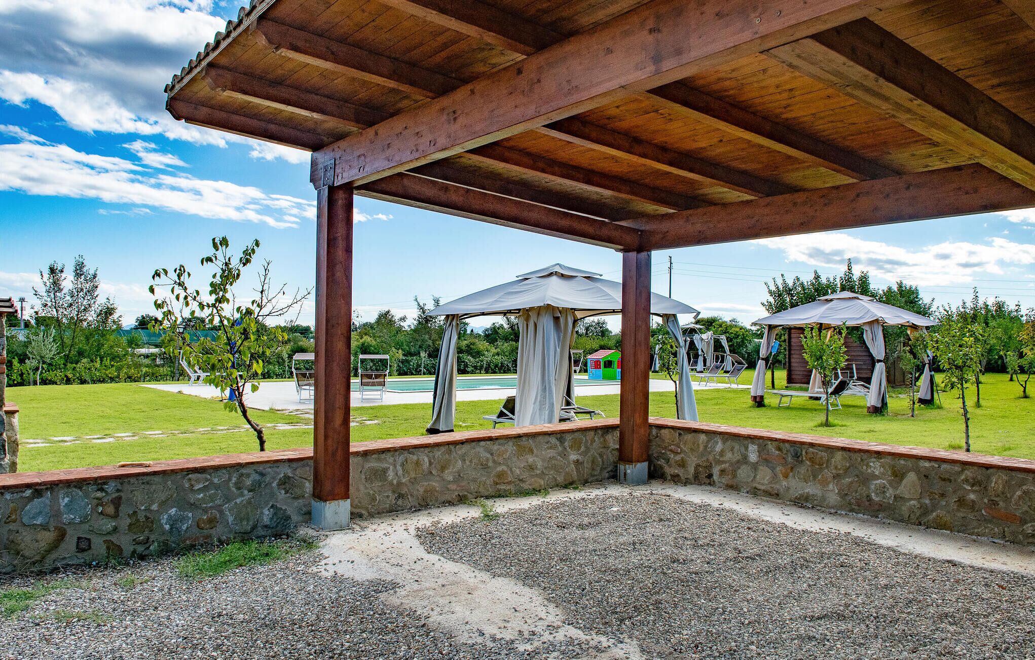 A covered outdoor area with stone walls and a gravel path.
