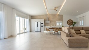 A spacious living area with a large beige sectional sofa, a dining table with chairs, and a kitchen in the background. - MalagaSuite Villa Nomada El Torcal (Antequera)