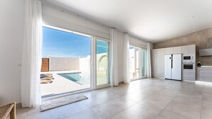 A spacious modern kitchen with a large island, a dining area, and a view of a swimming pool. - MalagaSuite Villa Nomada El Torcal (Antequera)