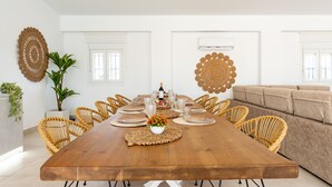 A dining area with a wooden table set for six, surrounded by wicker chairs. - MalagaSuite Villa Nomada El Torcal (Antequera)