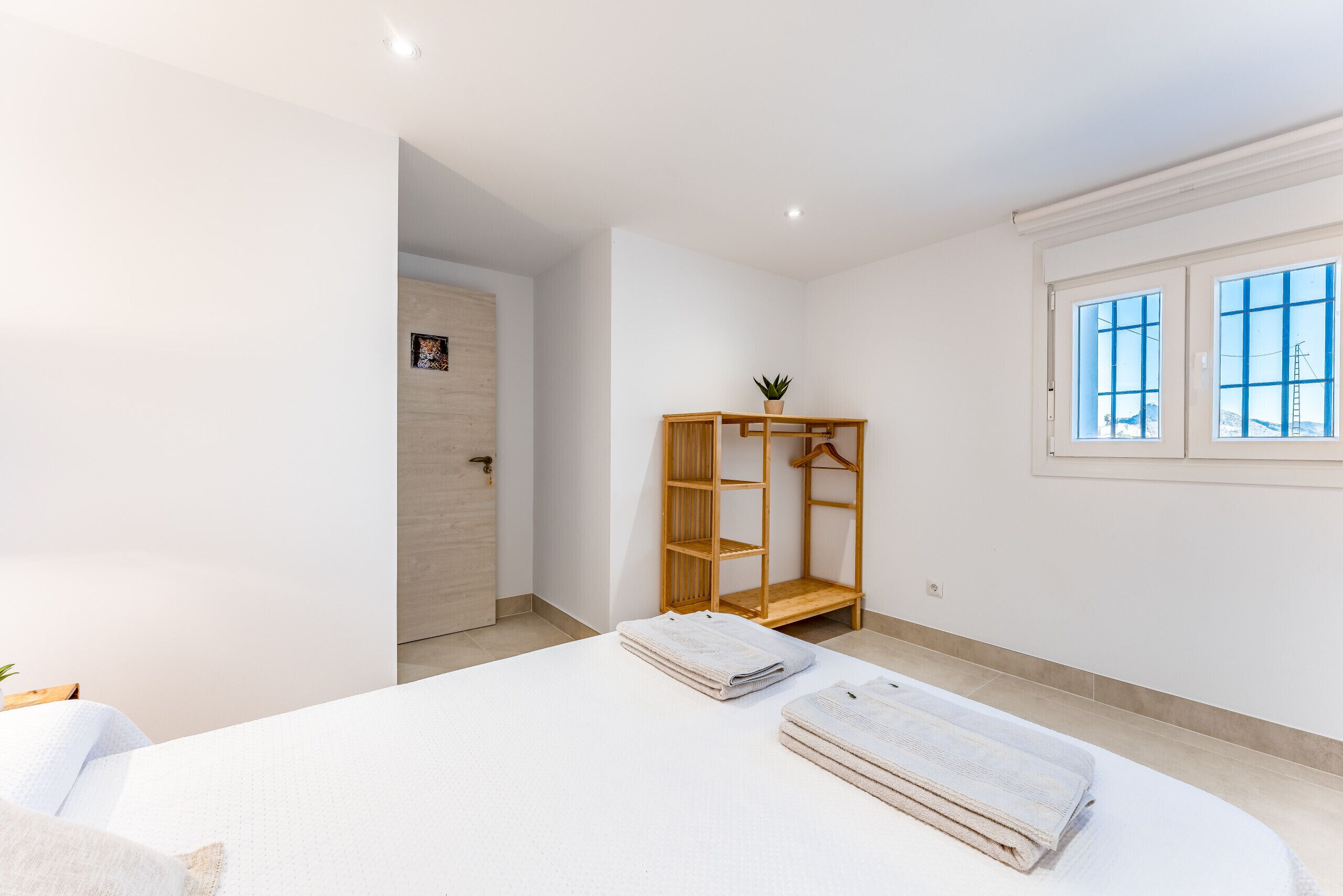 Un dormitorio con cama, armario de madera y ventana con vistas.