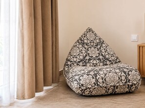 A bean bag chair with a patterned design, positioned against a wall with a light switch. - Bohemian Loft in Central Athens (Kypseli)