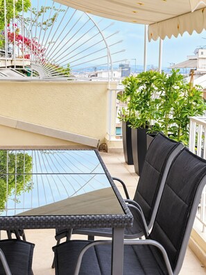 Ein Balkon mit Tisch und Stühlen, Blumentöpfen und Blick auf die Stadtlandschaft.
