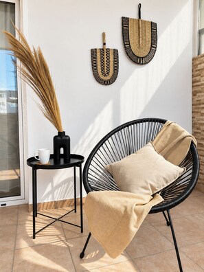 A modern interior with a black wire chair, a small round table with a white mug, and two woven wall decorations. - Funky Boho Kallithea Loft (Kallithea)