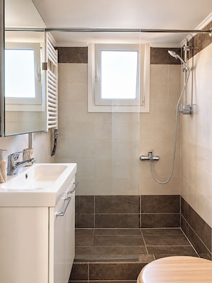 Un baño con ducha, lavabo y espejo.