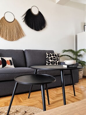 A modern living room with a grey sofa, two black tables, and a woven rug. - Funky Boho Kallithea Loft (Kallithea)