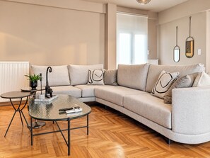 Una sala de estar moderna con un sofá seccional, una mesa de centro de vidrio y una mesita auxiliar con una planta.