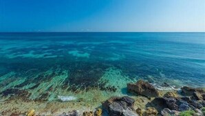 A coastal view with clear turquoise waters and rocky shoreline. - Roca Chaac South Studio (Isla Mujeres)