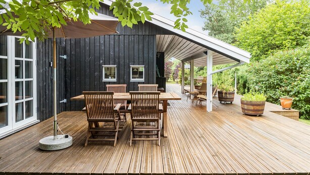 A wooden deck with a table and chairs, a covered patio area, and potted plants. - 4 bedroom gorgeous home in Hornbæk (Hornbæk)