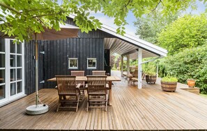 A wooden deck with a table and chairs, a covered patio area, and potted plants. - 4 bedroom gorgeous home in Hornbæk (Hornbæk)