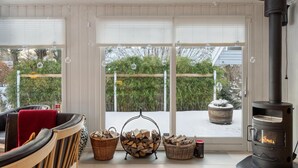 A cozy room with a fireplace, a sofa, and a view of a snowy garden through large windows. - 4 bedroom gorgeous home in Hornbæk (Hornbæk)