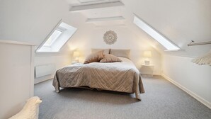 Une chambre à coucher avec un lit, deux lampes de chevet, un élément décoratif mural et une lucarne.