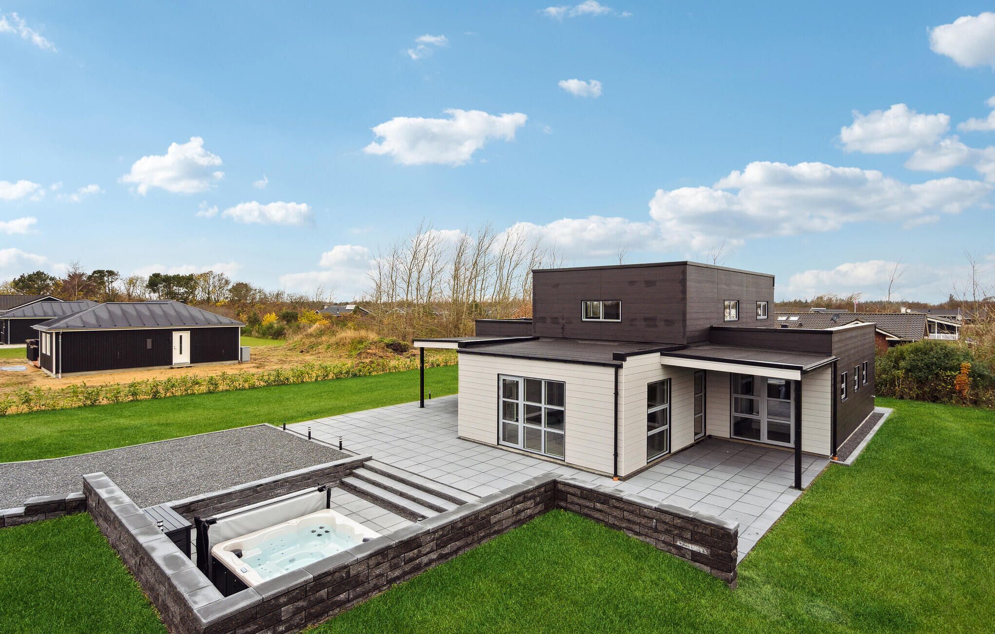 Een modern huis met twee verdiepingen, een ruime patio en een jacuzzi.