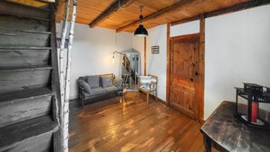 A wooden staircase leading to a loft area with a sofa and a chair, a wooden door, and a hanging light fixture. - 2 bedroom amazing home in Bas-en-Basset (Bas-en-Basset)