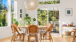 A dining area with a round table, wicker chairs, and a hanging light fixture. - Pirates Perch I Whidbey I Hot Tub I King Bed (Freeland)
