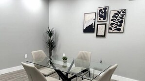 Un salón de conferencias con una mesa de vidrio, cuatro sillas y arte abstracto en la pared.