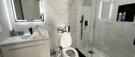 Une salle de bain moderne avec un meuble-lavabo blanc, des toilettes, une douche à parois de verre et un sol carrelé en marbre.