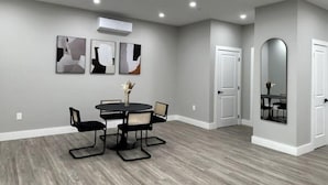 Un espace repas moderne avec une table ronde et des chaises, des murs gris et un plancher en bois.