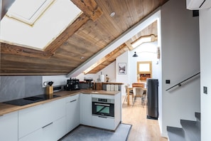 A modern kitchen with a skylight, wooden ceiling, and a view to a dining area.