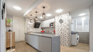 A modern kitchen with a central island, built-in appliances, and pendant lighting.