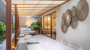 A modern outdoor seating area with a pergola, cushioned sofas, and decorative wall art. - Way Bossa por Carpediem (João Pessoa)