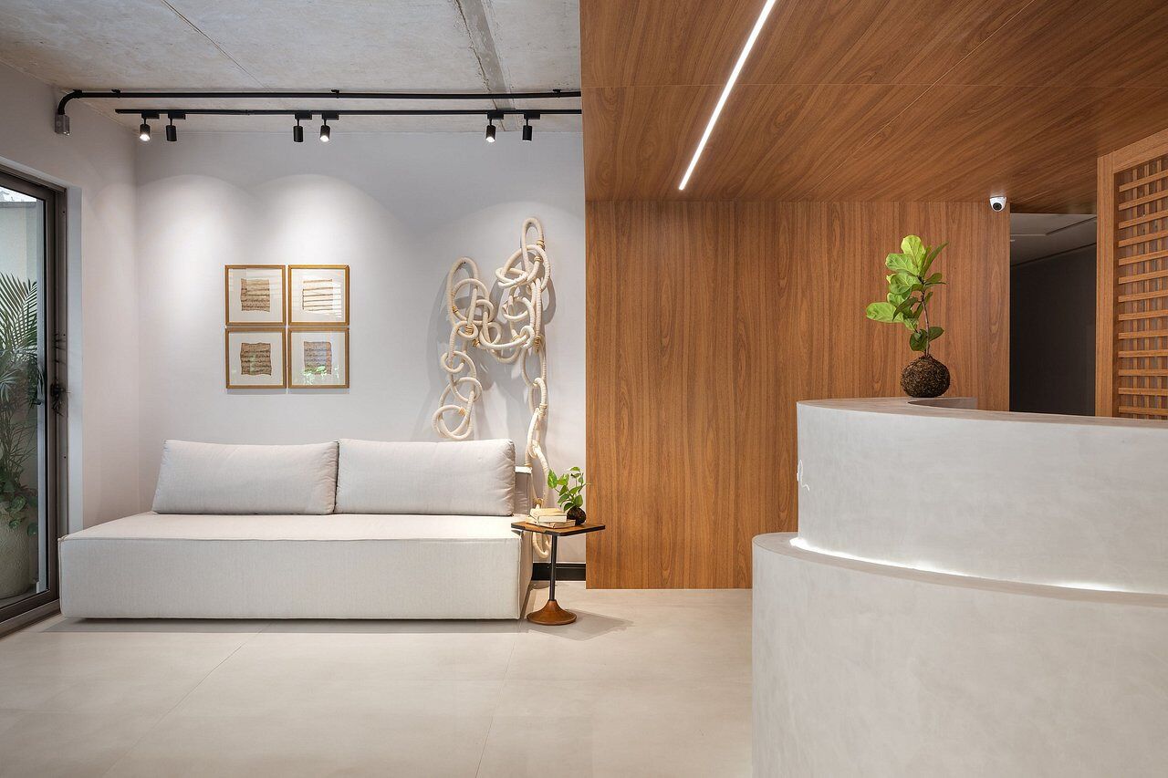 Un interno moderno con un divano bianco, opere d'arte astratte, una reception in legno e una pianta in vaso.