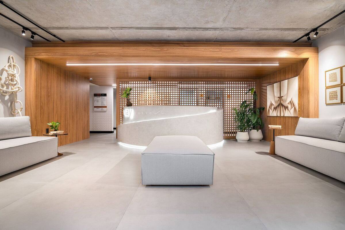 A modern reception area with a wooden reception desk, a seating area with sofas, and a decorative wall with plants.