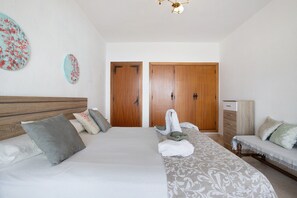 A bedroom with a bed, two wooden doors, a bedside table, and a lamp.