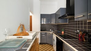 A compact kitchen with a washing machine, a sink, and a countertop with a checkered floor.