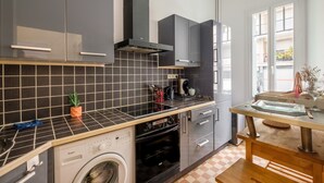 A modern kitchen with grey cabinets, a built-in oven, and a washing machine.