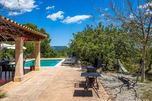 A poolside area with lounge chairs, a hammock, and a pergola.