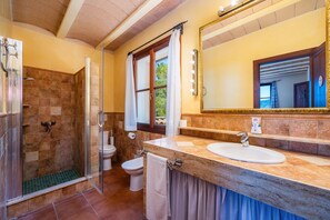 A bathroom with a shower, toilet, sink, and a large mirror.