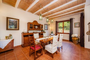 A dining area with wooden furniture, a tiled floor, and a window with curtains.