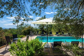 A swimming pool with lounge chairs and an umbrella, surrounded by greenery and trees. - Villa 'Finca Moscari' with Private Pool, Wi-Fi and Air Conditioning (Moscari)