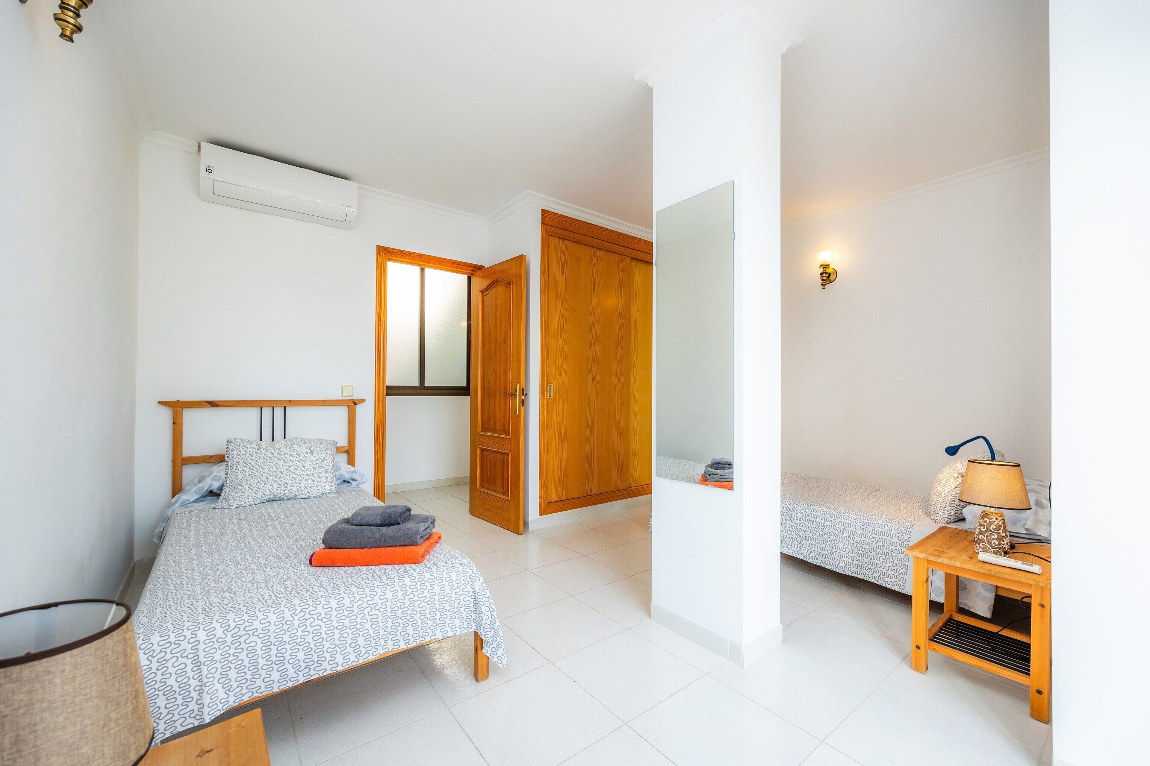 Een slaapkamer met een bed, nachtkastje, lamp en een airconditioning.