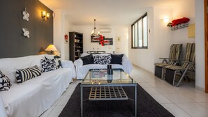 En moderne stue med sofa, sofabord i glas og stribede stole.