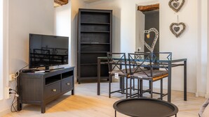 A modern living room with a flat-screen TV, dark wooden furniture, and decorative heart-shaped wall art. - Apartment 'Can Roses' with Private Terrace, Wi-Fi and Air Conditioning (Moscari)