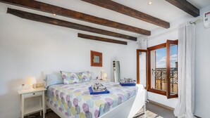 Un dormitorio con cama, mesita de noche, lámpara y ventana con vistas.