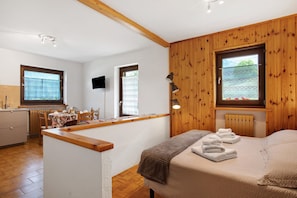 A bedroom with a bed, a bedside table, a lamp, and a view of the outdoors through a window. - Holiday Home 'Le Cré Appartamento 2' with Mountain View, Shared Garden and Wi-Fi (Introd)