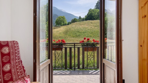 A balcony with a view of a grassy hill and mountains. - Holiday Home 'Le Cré Appartamento 2' with Mountain View, Shared Garden and Wi-Fi (Introd)