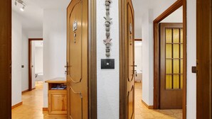 A hallway with wooden doors, a small cabinet, and a wall-mounted light switch. - Holiday Home 'Le Cré Appartamento 5' with Mountain View, Shared Garden and Wi-Fi (Introd AO)