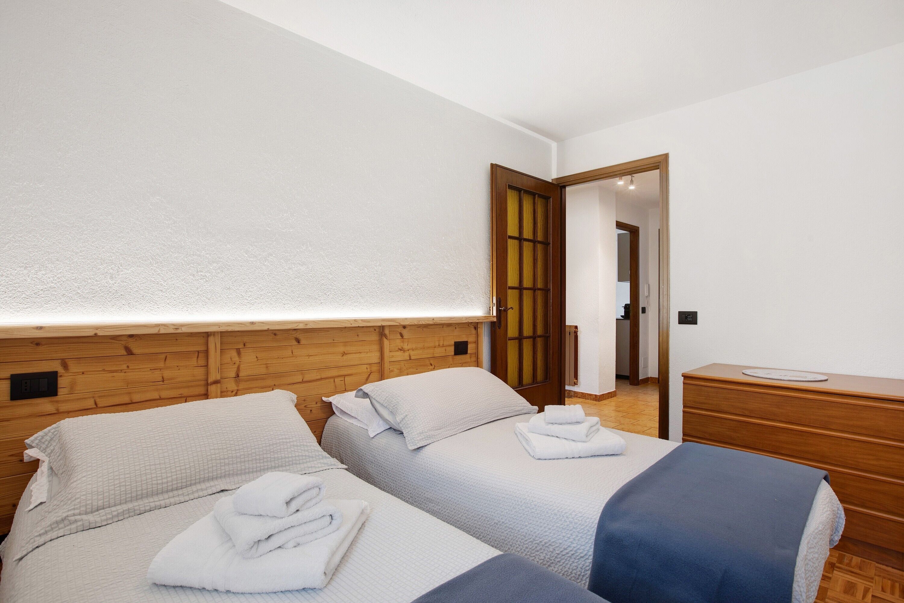 Ein Hotelzimmer mit zwei Betten, einem Holzkopfstück, einem Nachttisch und einem Spiegel.