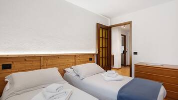 Ein Hotelzimmer mit zwei Betten, einem Holzkopfstück, einem Nachttisch und einem Spiegel.