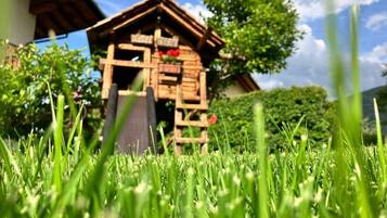 Eine hölzerne Konstruktion mit geneigtem Dach, umgeben von grünem Gras und blauem Himmel.