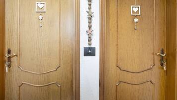 Dos puertas de madera con un hilo vertical de adornos y un interruptor de luz entre ellas.