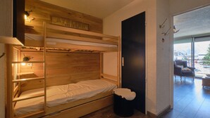 A bunk bed with a wooden headboard, a small bedside table, and a trash bin. - Studio "2 Alpes" with Mountain View, Private Terrace, and Balcony (Les Deux Alpes)