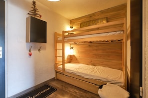 Un lit superposé avec une tête de lit en bois, un paillasson et un panneau fixé au mur.